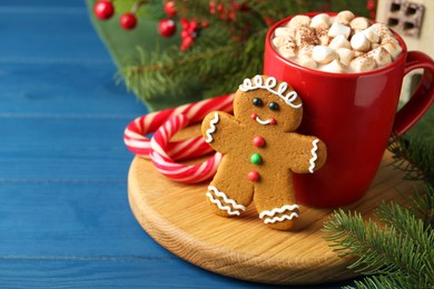 Tasty gingerbread man cookie and cocoa with marshmallows on blue wooden table, closeup. Space for text
