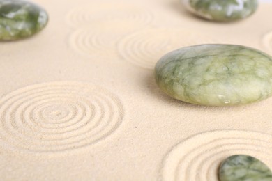 Photo of Zen garden stones on beige sand with pattern, closeup