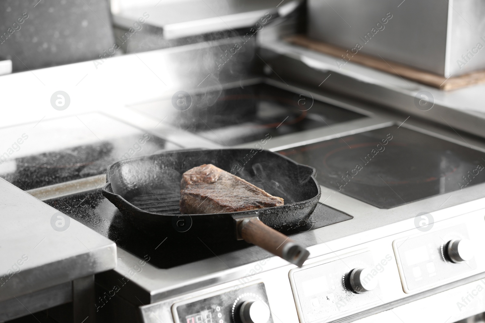 Photo of Cooking delicious meat on frying pan in restaurant kitchen