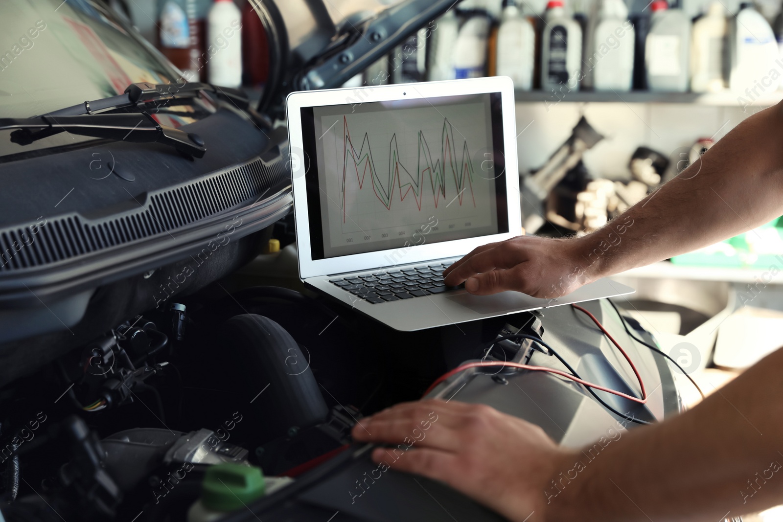 Photo of Mechanic with laptop doing car diagnostic at automobile repair shop, closeup