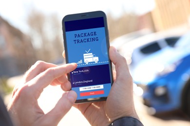 Image of Man tracking parcel via smartphone outdoors, closeup