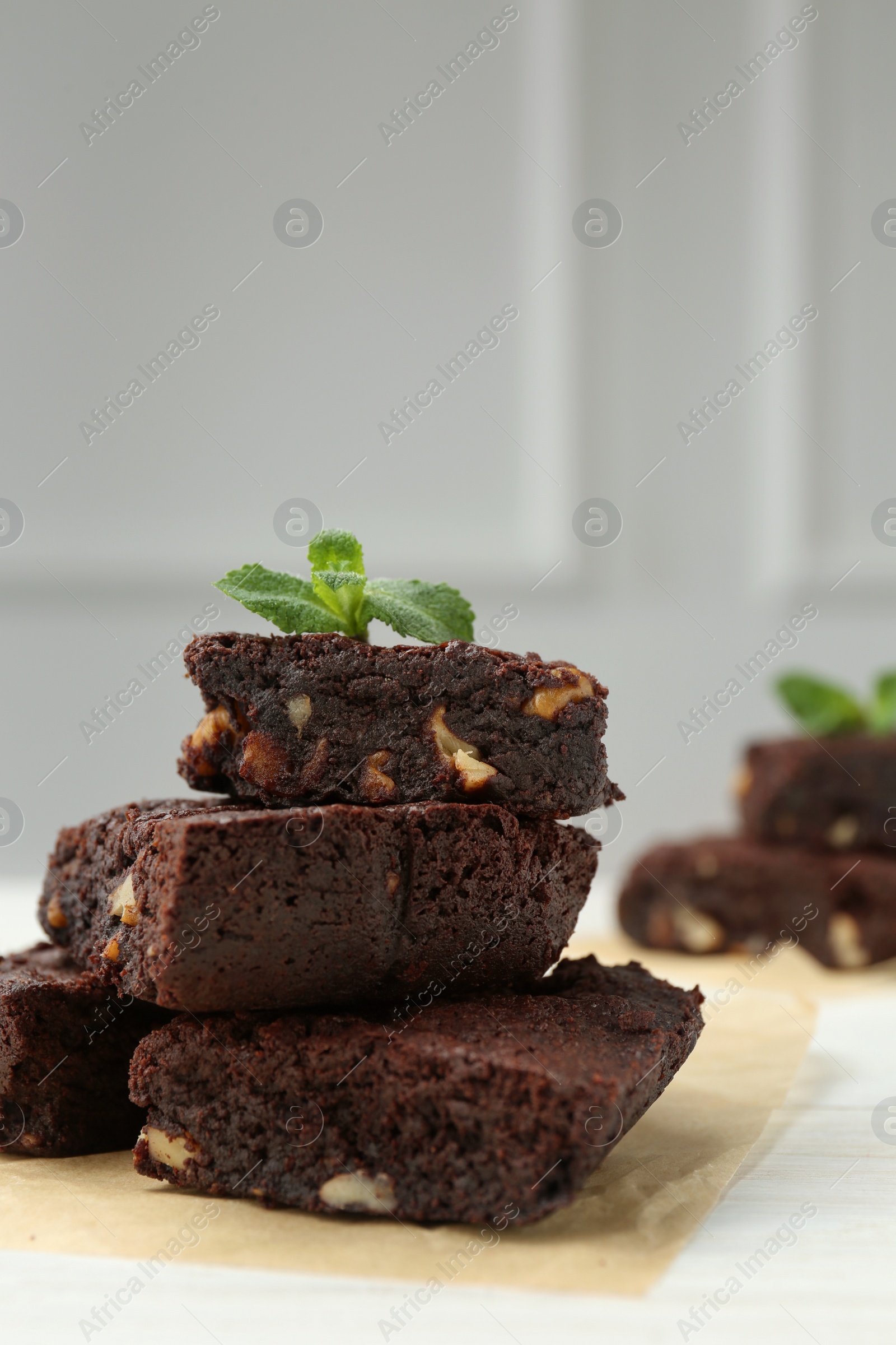 Photo of Delicious chocolate brownies with nuts and fresh mint on white table, closeup