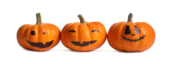 Photo of Halloween pumpkins with cute drawn faces on white background