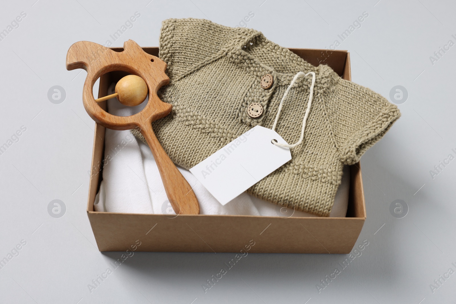 Photo of Different baby accessories, clothes and blank card in box on light grey background