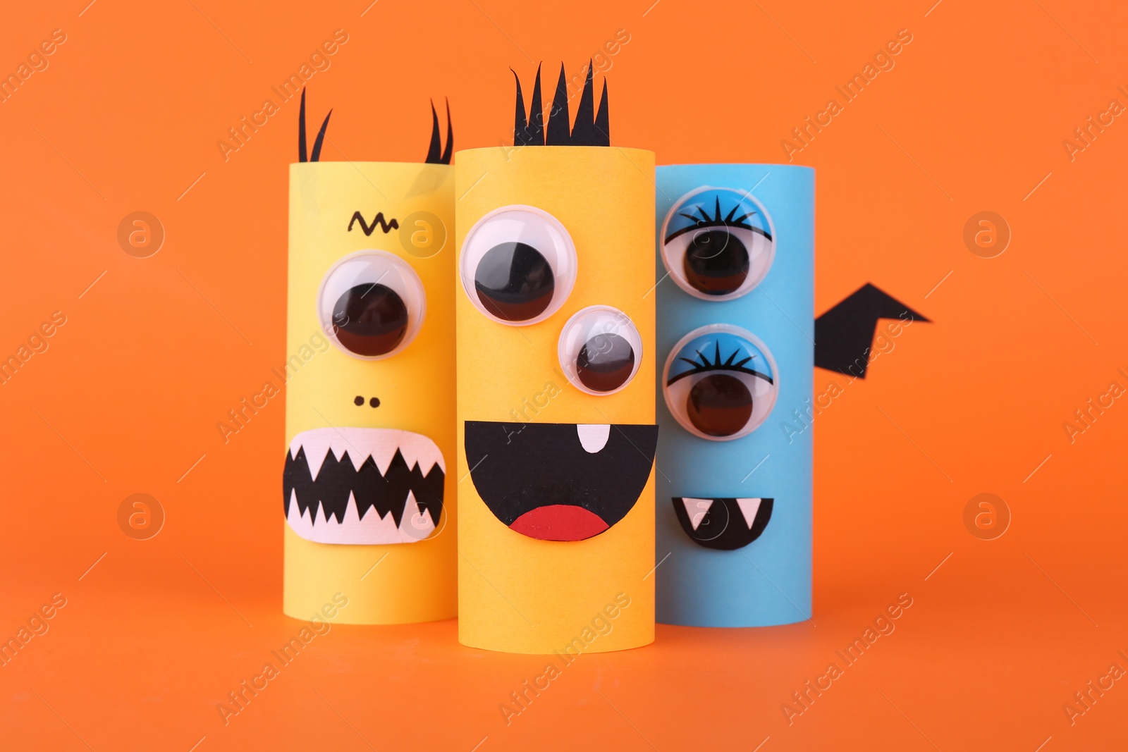 Photo of Spooky paper monsters on orange background. Handmade Halloween decoration