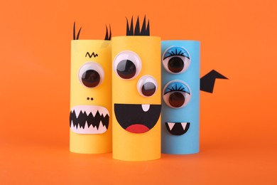 Photo of Spooky paper monsters on orange background. Handmade Halloween decoration