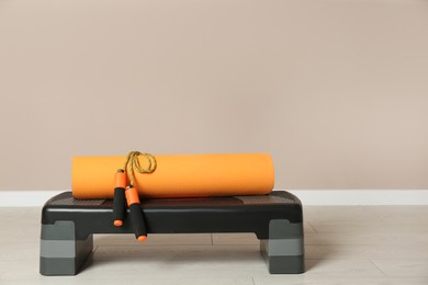 Photo of Step platform, mat and jump rope indoors. Sports equipment