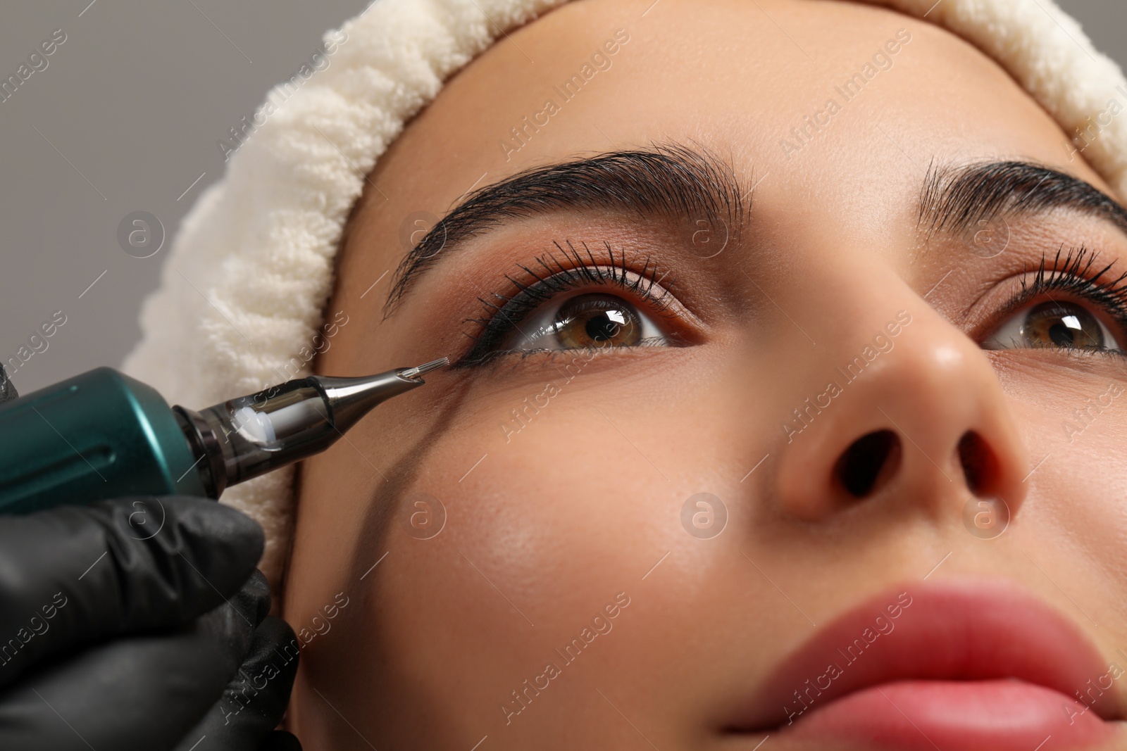 Photo of Young woman undergoing procedure of permanent eyeliner makeup, closeup