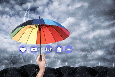 Insurance agent covering illustrations with rainbow umbrella during storm