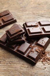 Pieces of tasty chocolate on wooden background