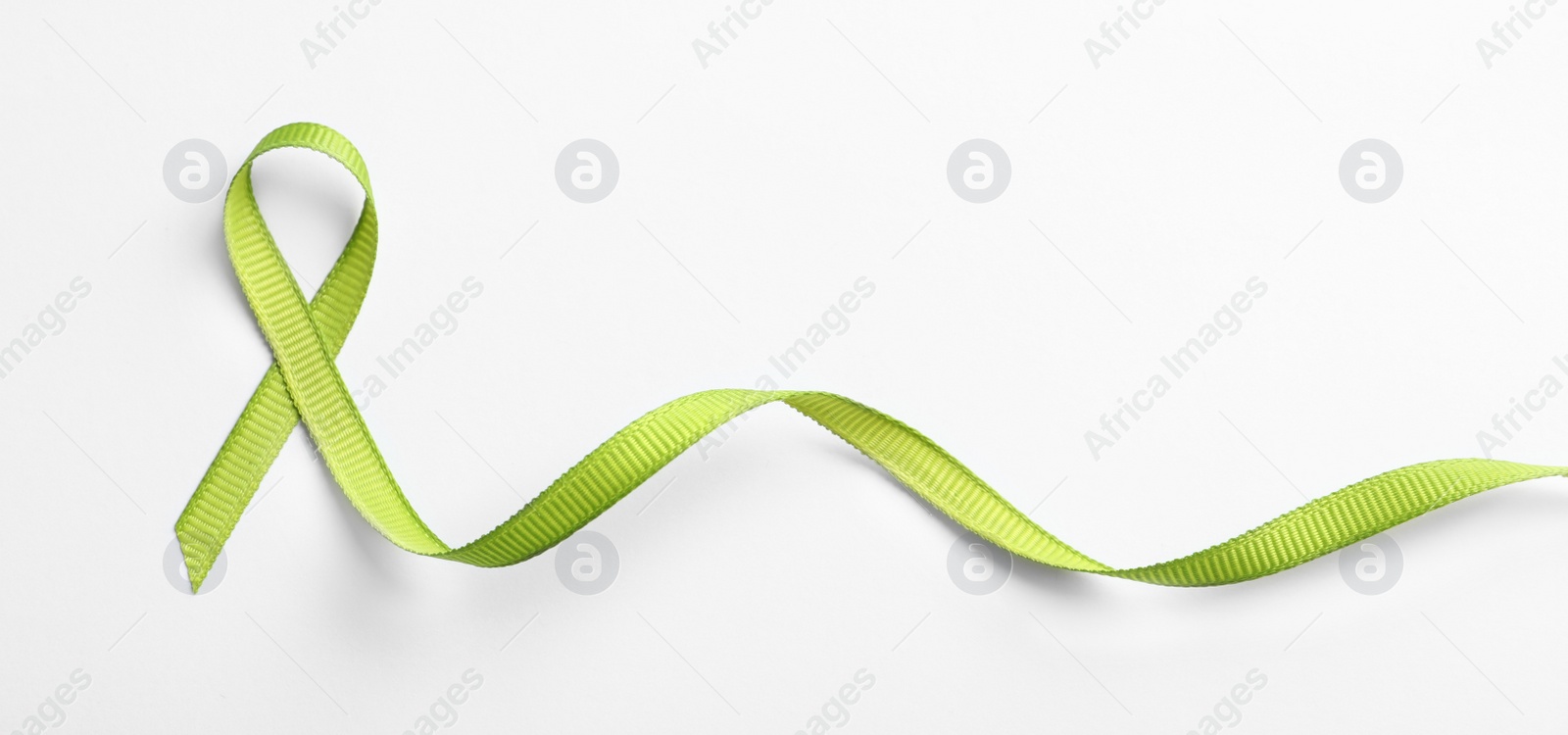 Photo of Green ribbon on white background, top view. Cancer awareness