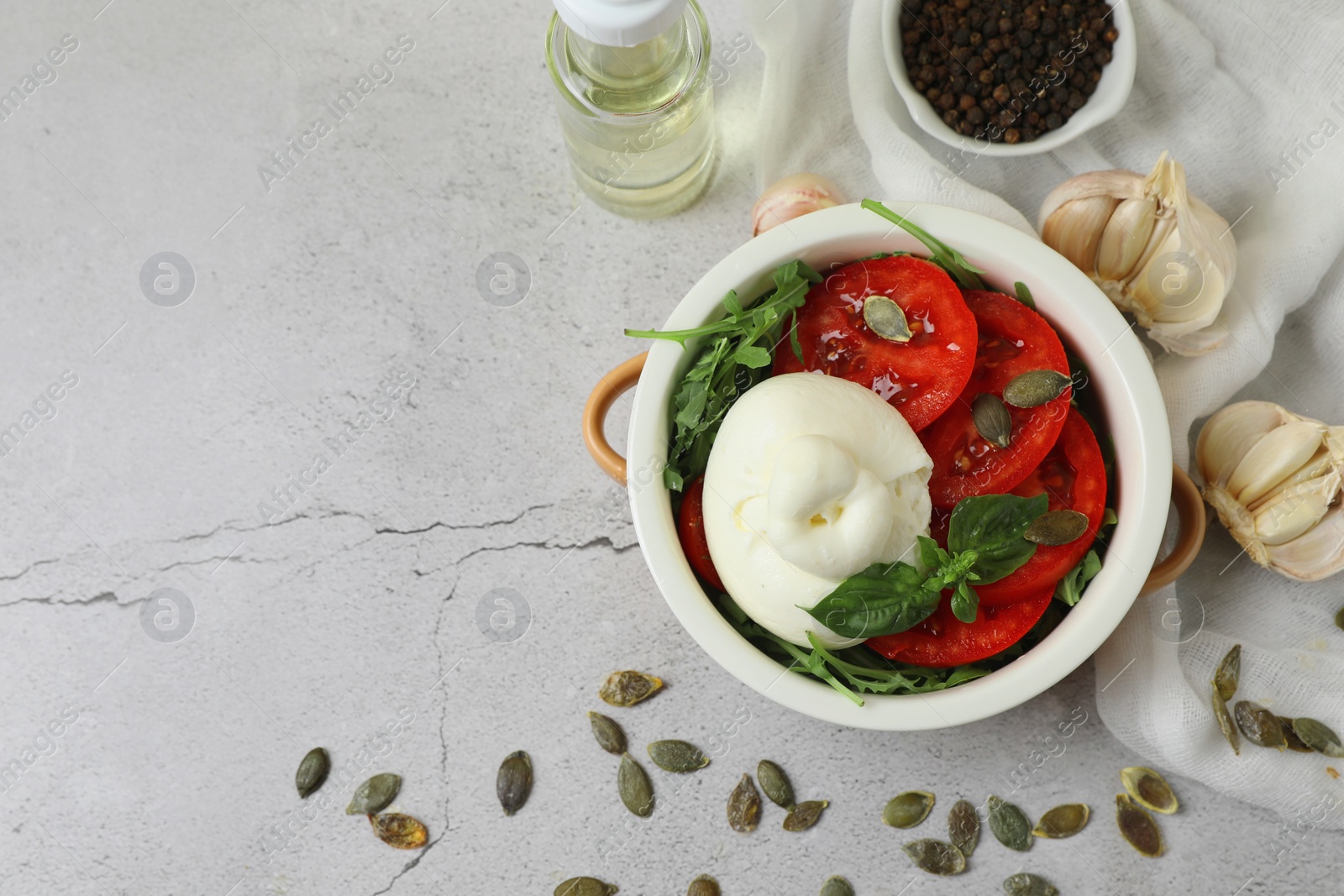 Photo of Flat lay composition with delicious burrata cheese, tomatoes and pumpkin seeds on light grey table, space for text
