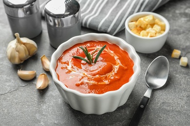 Fresh homemade tomato soup served with croutons and garlic on grey table