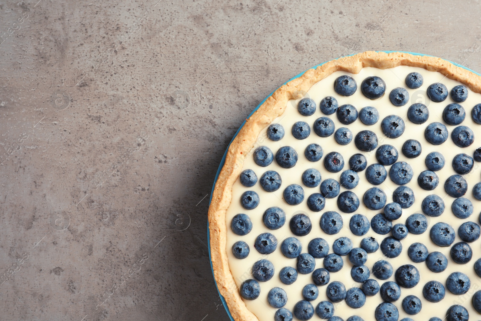 Photo of Tasty blueberry cake on gray background, top view with space for text