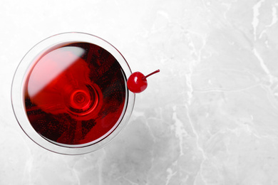 Glass of fresh cocktail with cherry on marble table, top view. Space for text