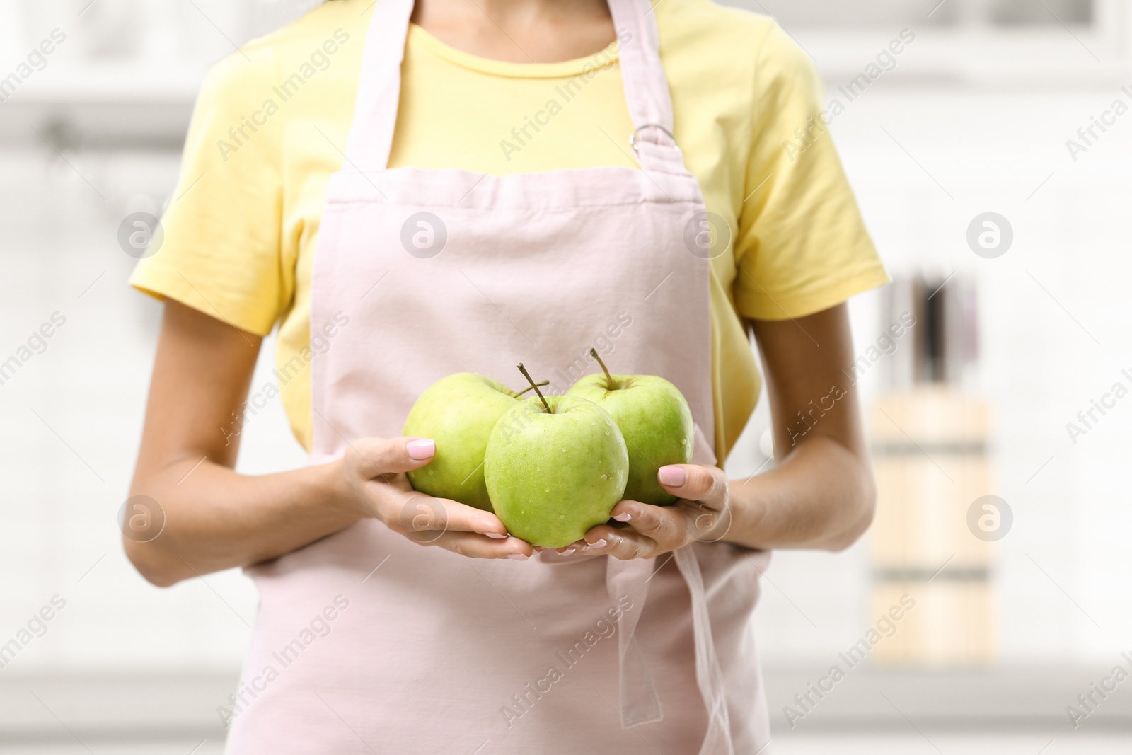 Photo of Woman holding fresh apples in kitchen, closeup