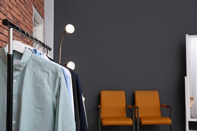 Photo of Wardrobe rack with stylish clothes in dressing room. Space for text