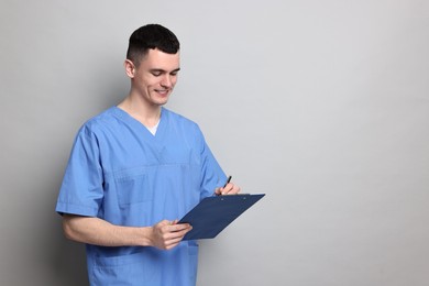 Photo of Portrait of smiling medical assistant with clipboard on grey background. Space for text