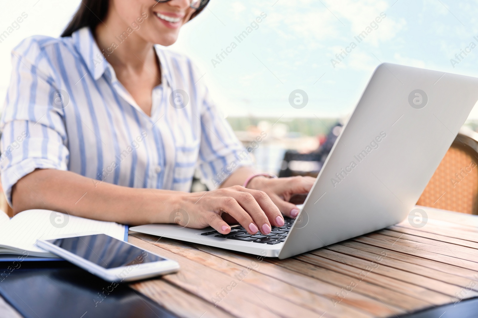 Photo of Woman using laptop at outdoor cafe, closeup