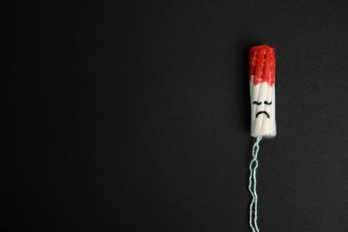 Photo of Used tampon on black background, top view. Space for text