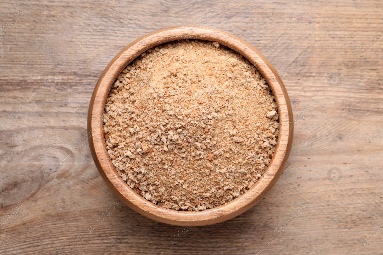 Photo of Fresh breadcrumbs in bowl on wooden table, top view