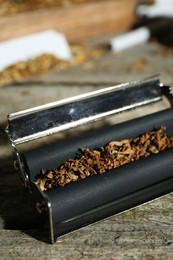 Roller with tobacco on old wooden table, closeup. Making hand rolled cigarettes