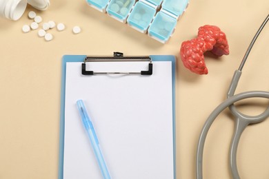 Photo of Endocrinology. Flat lay composition with clipboard and model of thyroid gland on beige background