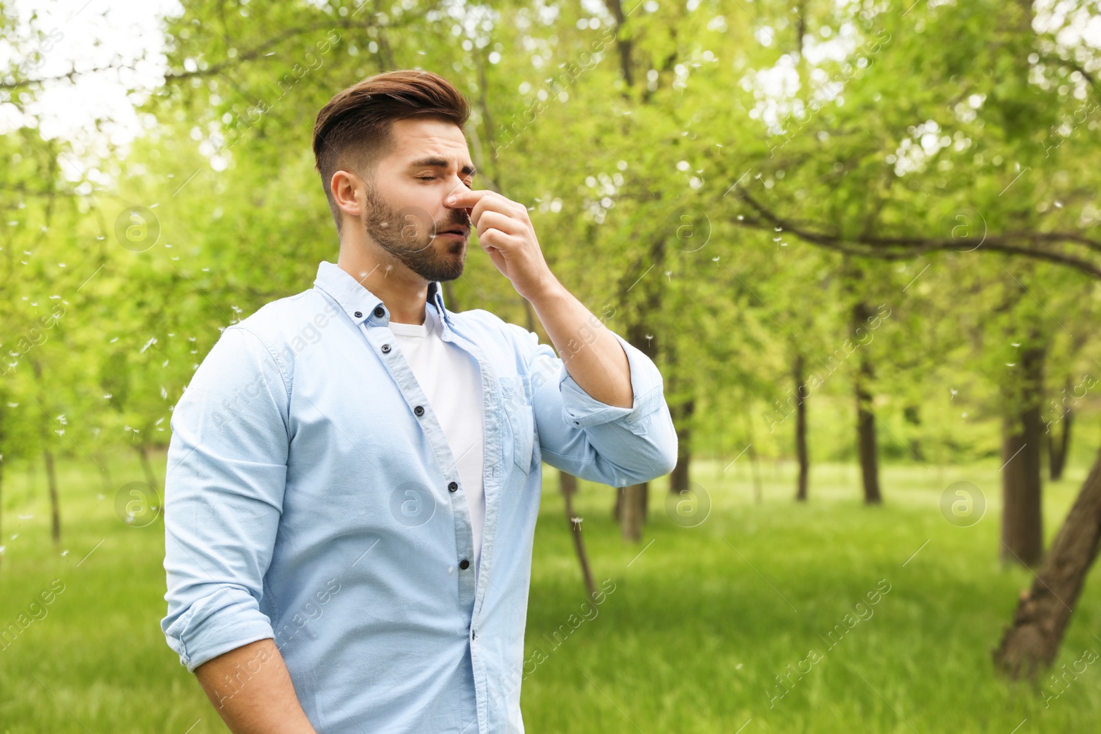 Photo of Young man suffering from seasonal allergy outdoors, space for text