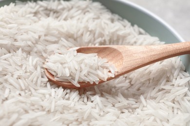 Photo of Raw basmati rice in bowl and spoon, closeup