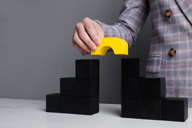 Photo of Businesswoman building bridge with colorful blocks at table, closeup. Connection, relationships and deal concept