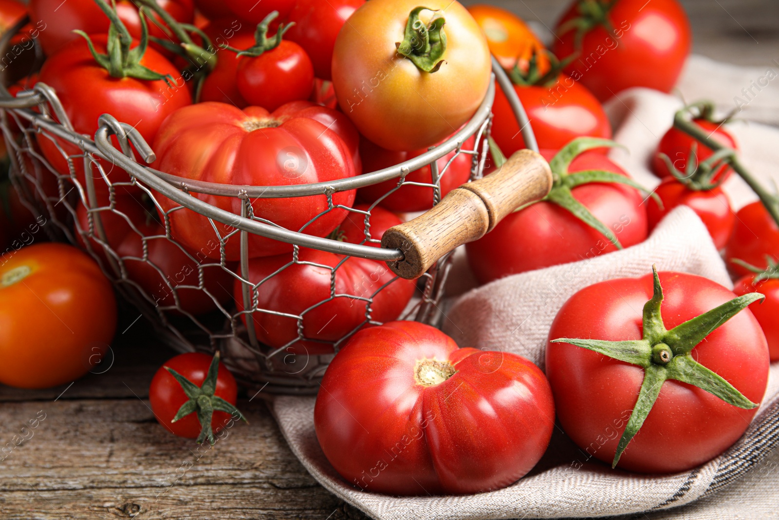 Photo of Many different ripe tomatoes on wooden table, closeup