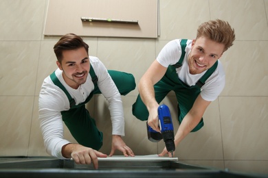 Photo of Young workers installing drywall indoors, above view. Home repair service