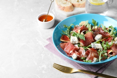 Salad with ripe figs and prosciutto served on grey marble table. Space for text