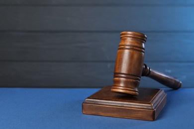 Photo of Wooden gavel on blue table, closeup. Space for text