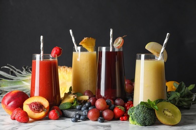 Photo of Glasses of delicious juices and fresh ingredients on white marble table