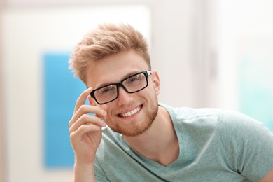 Portrait of handsome young man with glasses in room