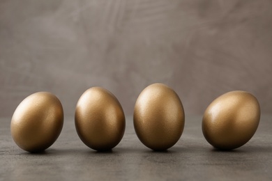 Photo of Many shiny golden eggs on grey table