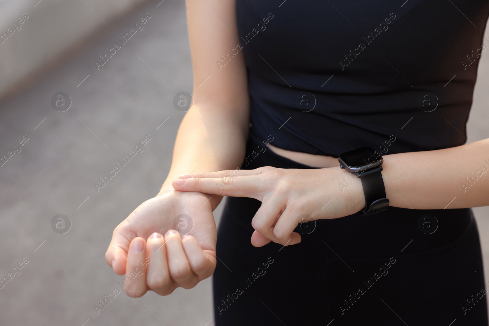 Photo of Woman checking pulse after training outdoors, closeup