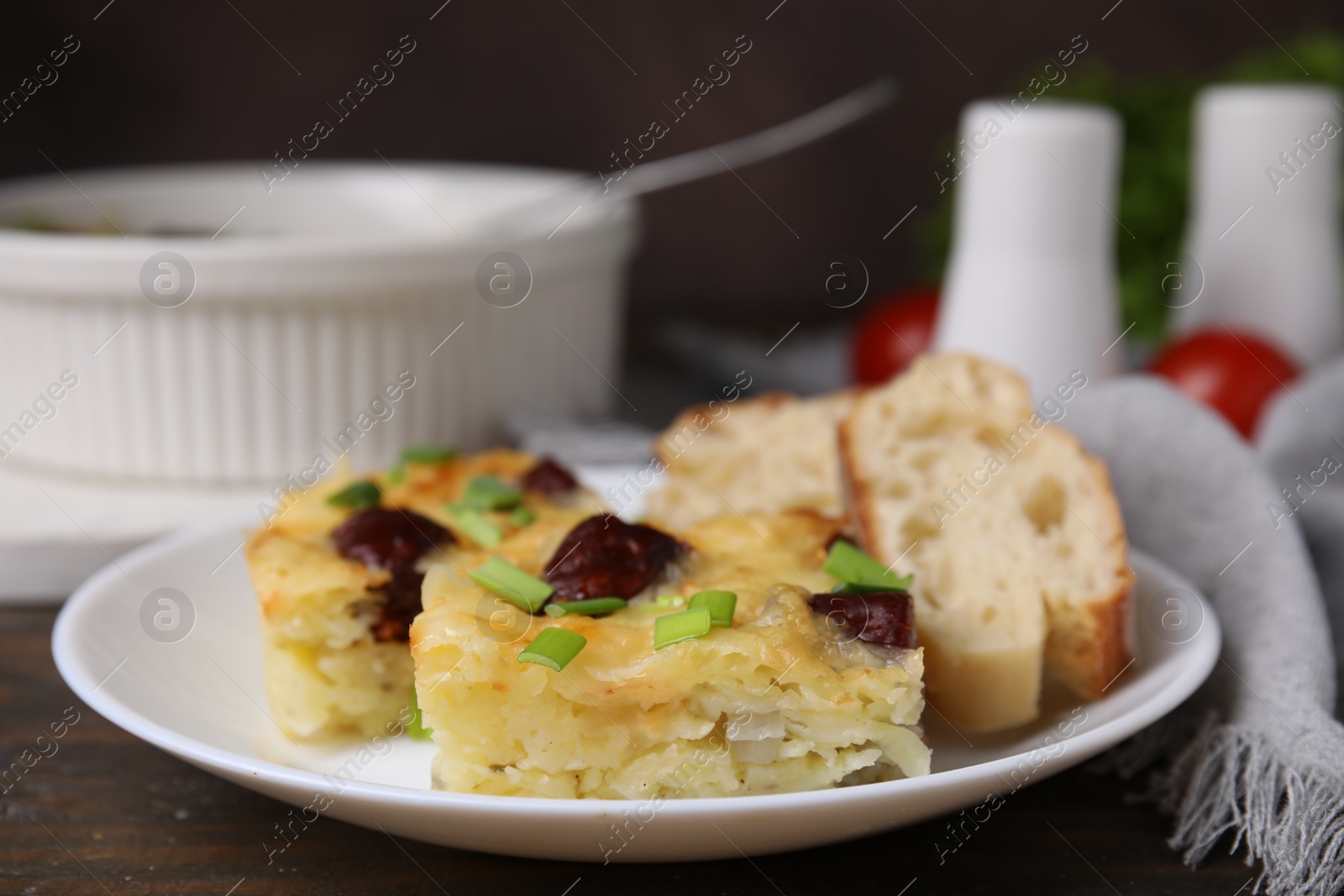 Photo of Tasty sausage casserole with green onion and bread on wooden table, closeup