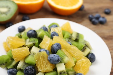 Plate of tasty fruit salad on table, closeup