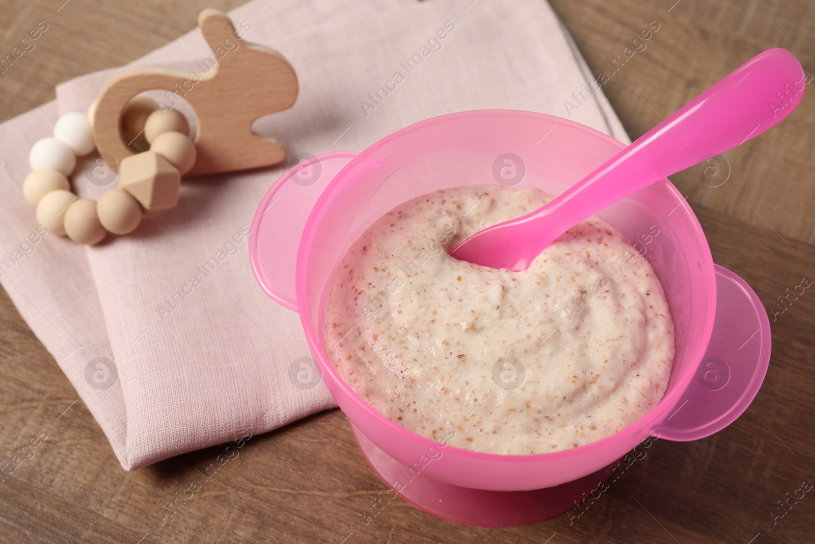 Photo of Baby food. Puree in bowl and toy on wooden table