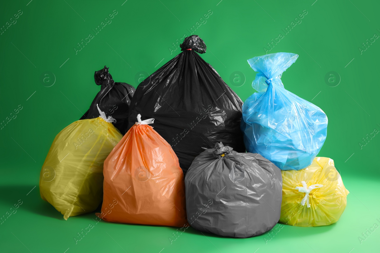 Photo of Trash bags full of garbage on green background