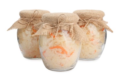 Photo of Glass jars of tasty fermented cabbage with carrot on white background