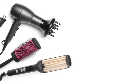 Hair dryer, round brush and triple curling iron on white background, top view