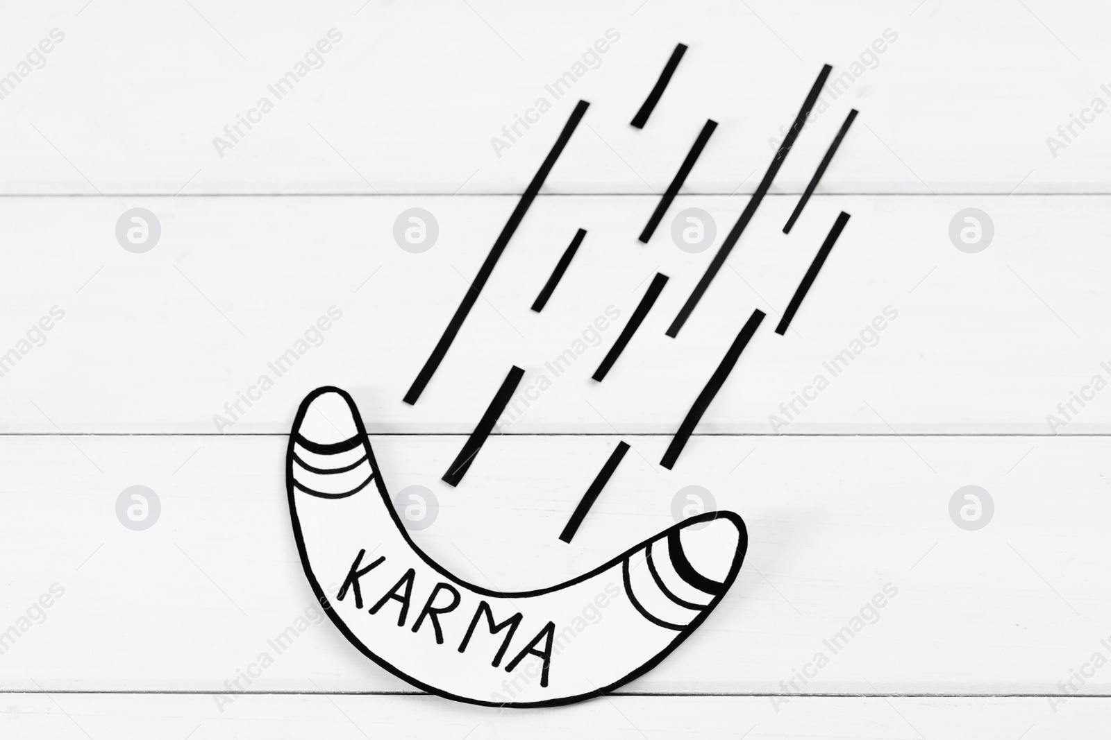 Photo of Paper boomerang with word Karma on white wooden table, flat lay