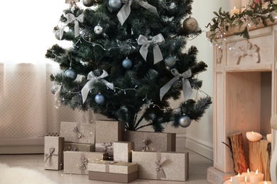 Photo of Decorated Christmas tree with gift boxes and fireplace in stylish living room interior