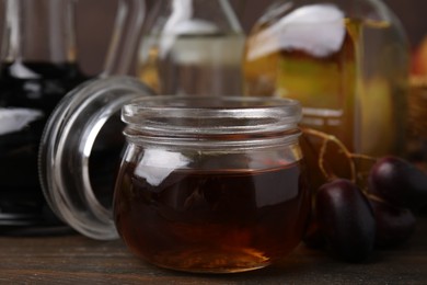 Different types of vinegar and grapes on wooden table, closeup