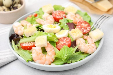 Photo of Delicious Caesar salad with shrimps on light table, closeup