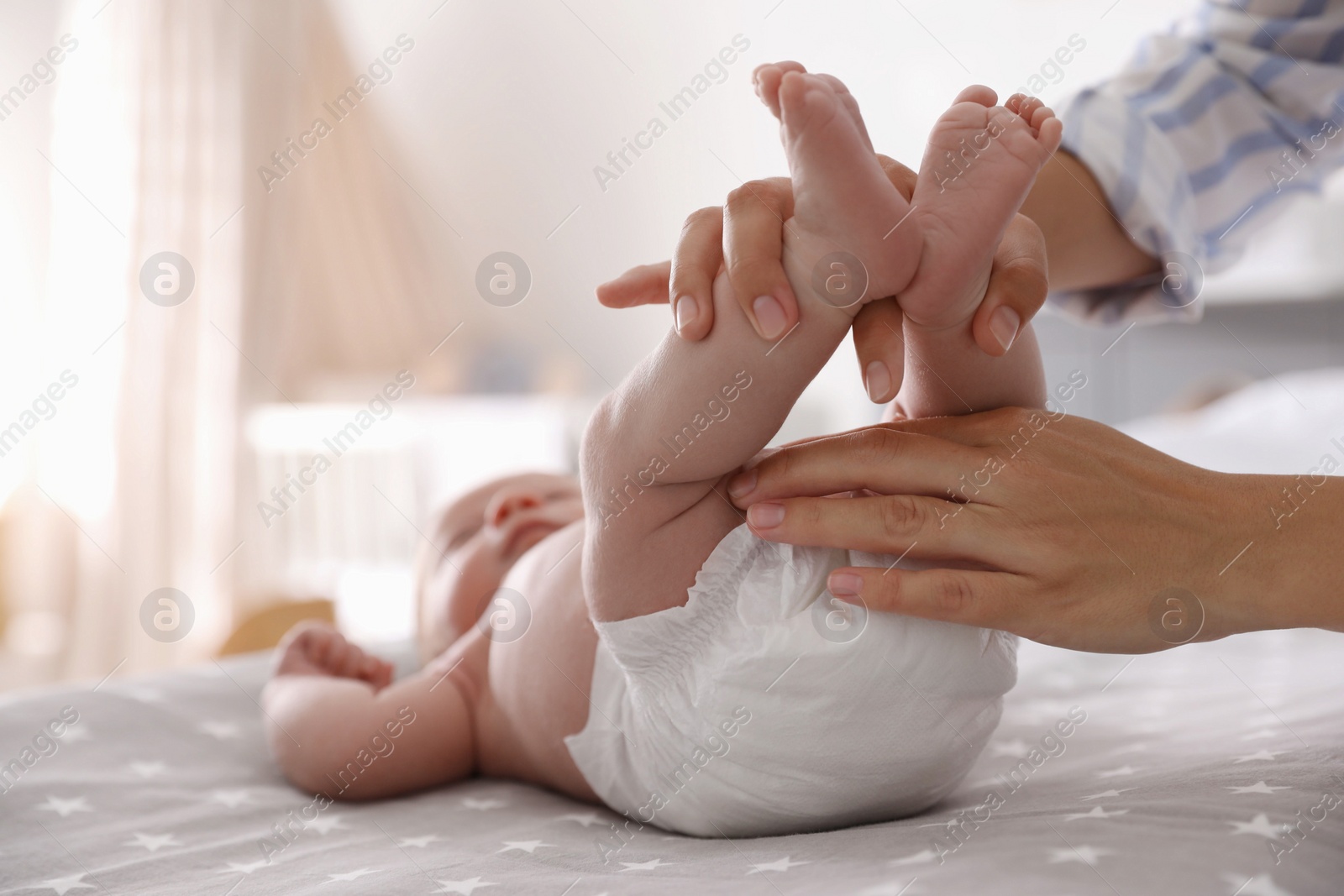 Photo of Mother changing her baby's diaper on bed