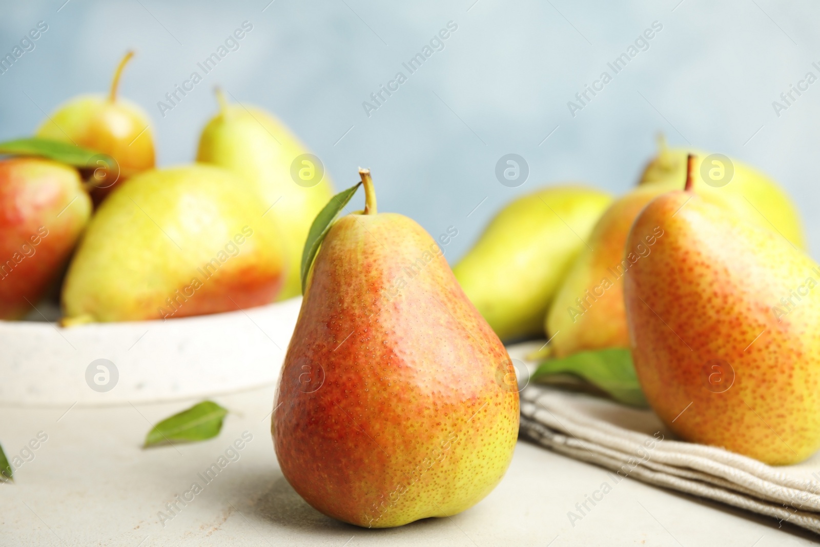 Photo of Ripe juicy pears on white stone table against blue background